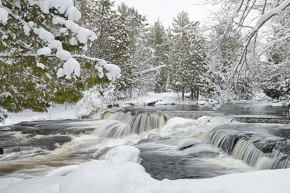 "A fresh blanket of snow surrounds Upper Bond Falls on a crisp winter morning"